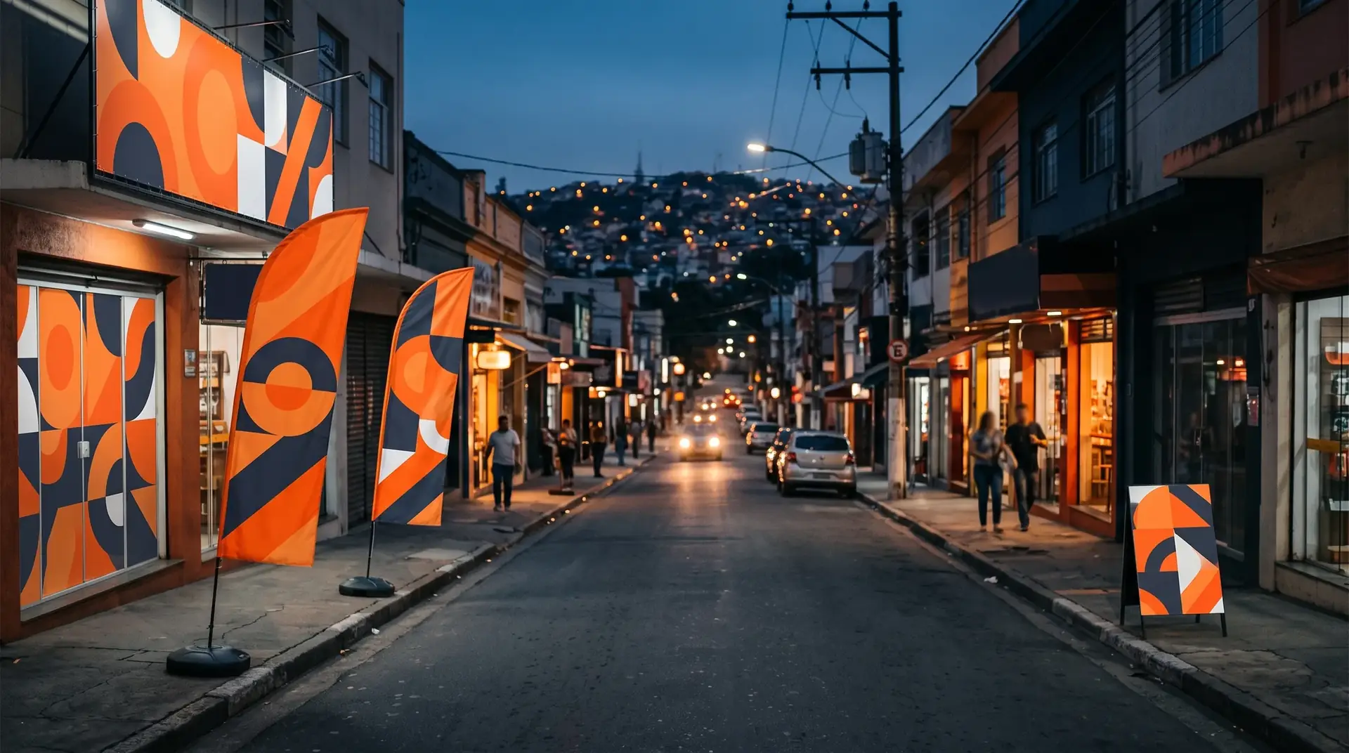 Rua comercial ao anoitecer com wind banners na calçada, lona na fachada e adesivo de vitrine nas lojas